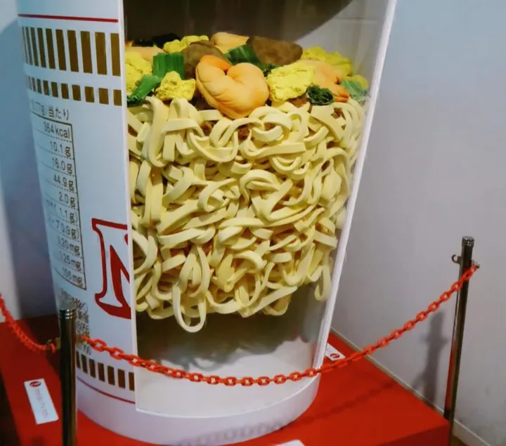 A larger-than-life cross-section display of an instant ramen cup.