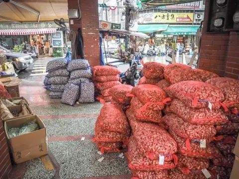 Bags of dried shallots and garlic for sale.
