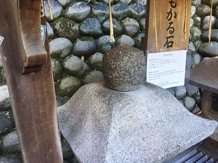 Omokaru-ishi, the "heavy-light" fortune stone near the summit shrine — lift it after making a wish; lighter than expected means the wish comes true.
