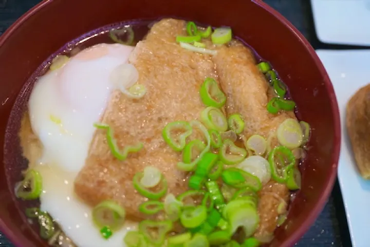 Kitsune tsukimi udon — udon topped with sweet fried tofu and a raw egg, named for the fox messengers of Inari.