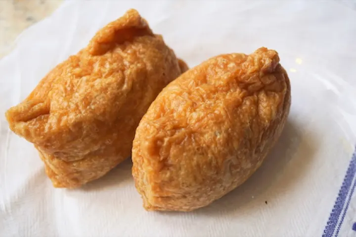 Inari-zushi, sushi rice stuffed into sweet fried tofu pouches — a local specialty named directly after the shrine's deity.