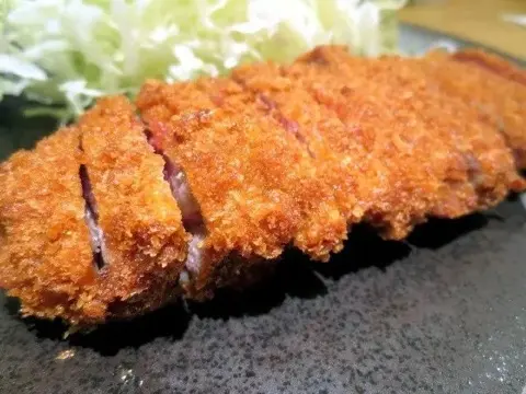A cut beef cutlet, showing the medium-rare center.