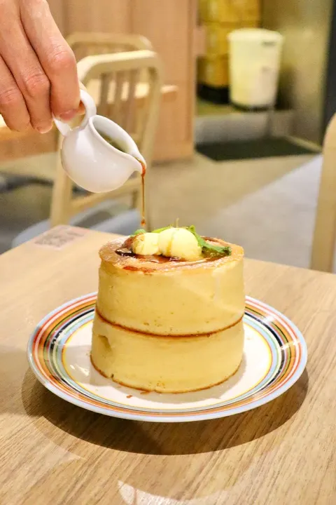 A tall Japanese-style souffle pancake at UZNA OMOM, served with butter and syrup.
