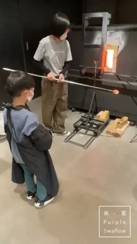 Kids shaping molten glass over the furnace with an instructor.