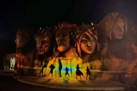 Hokage Rock lit up at night with projection mapping.
