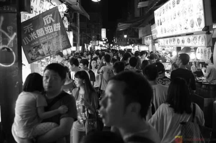 A crowded alleyway lined with food stalls at Shilin Night Market.