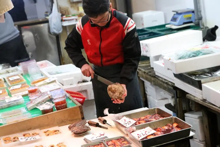A vendor preparing fresh shellfish to order.